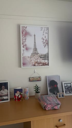 Customer's Eiffel Vista Art Print in a white frame, showing the Eiffel Tower in spring, hung on a wall above a dresser.