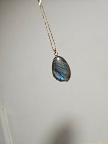 Le collier en labradorite d'un client avec son pendentif en pierre grise aux reflets bleus.