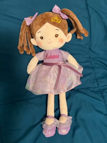Customer's personalized Princess Coral doll in a violet dress, with the name 'Makenna' embroidered on its chest.