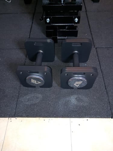 Kundenbild der zwei verstellbaren QUAD Kurzhanteln auf einer schwarzen Fitnessmatte.