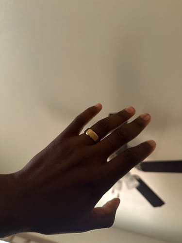 Reviewer's hand wearing the wide, gold-toned Midas ring.