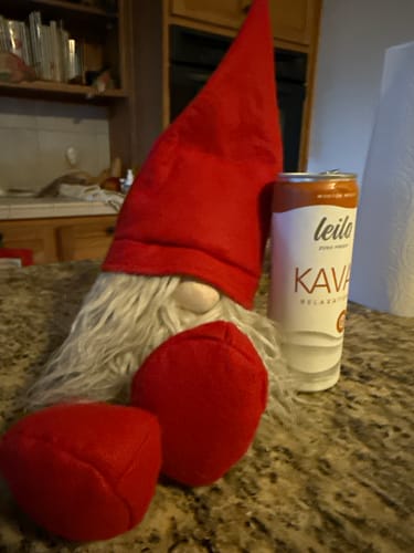 Customer's can of Leilo Kava Tonic next to a decorative red gnome on a kitchen counter.