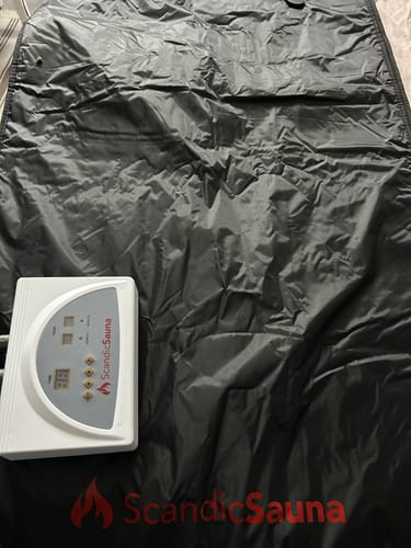 Kundens sorte Infrarødt Saunatæppe lagt ud med den hvide kontrolenhed ved siden af.