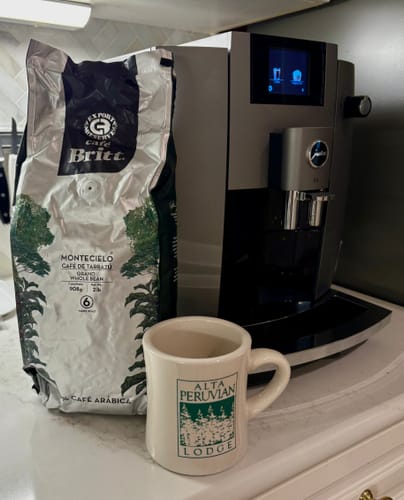 Customer's bag of Montecielo coffee from Tarrazú on a counter beside a coffee machine and a mug.