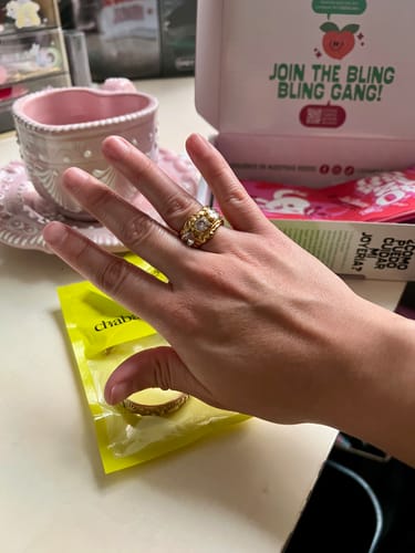 Cliente mostrando su Anillo Apolonia dorado en la mano, con un diseño grueso y piedras blancas.