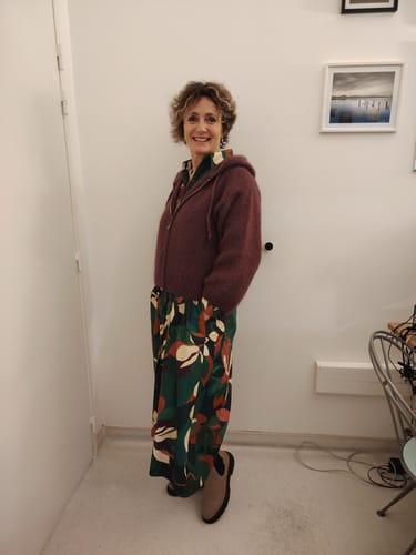 Cliente portant la Robe Pensée à motifs sous un gilet à capuche duveteux.