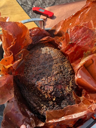 Customer's cooked USDA Prime Brisket with a dark seasoned crust, resting in butcher paper.
