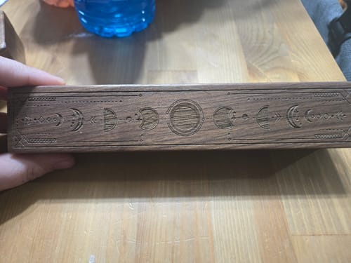Customer holding the long URWizards Engraved Walnut D&D Dice Box, showing the moon phase carvings on its side.
