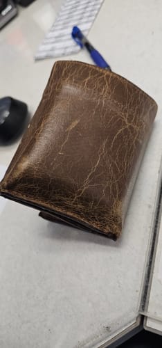 Close-up of a customer's Fontana Bison Trifold wallet, showing its worn, brown leather.