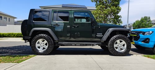 Customer's dark green Jeep looking very clean and shiny on a driveway after using the 4WD care package.