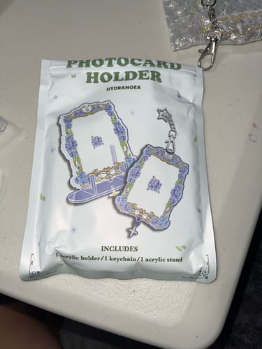 Customer shows the white packaging for the HYDRANGEA ACRYLIC PHOTOCARD HOLDER on a desk.