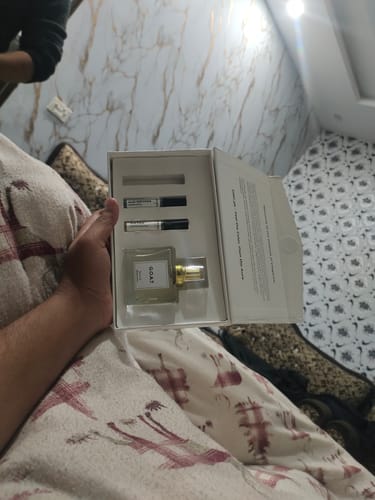 Customer holding the open G.O.A.T premium packaging, showing the perfume bottle and two sample vials inside.