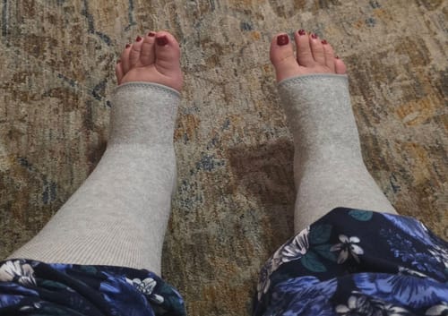 Customer's point-of-view wearing the light grey Premium Anti-Fatigue Bamboo Footsleeves on both legs.