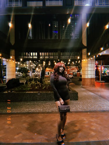 Reviewer standing outdoors at night wearing the dark Butter Turtleneck Contour Bodysuit.