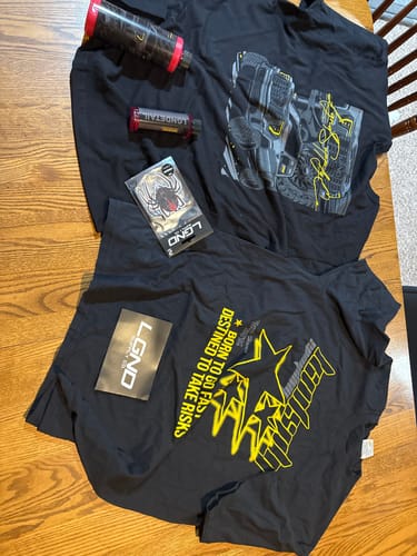 Customer's items from a LGND82™ Mystery CASH Box, including two black graphic t-shirts, detailing spray, and an air freshener.