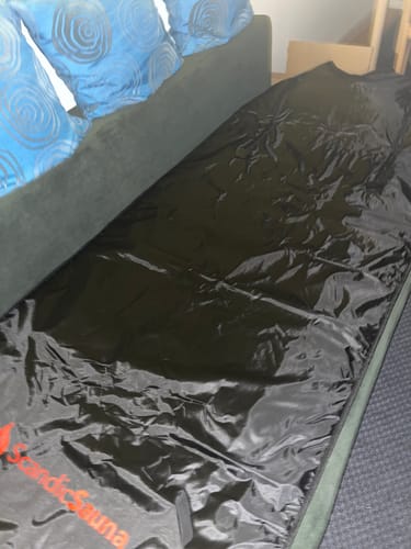 Kundes sorte Infrarødt Saunatæppe, der er foldet ud på en sofa.