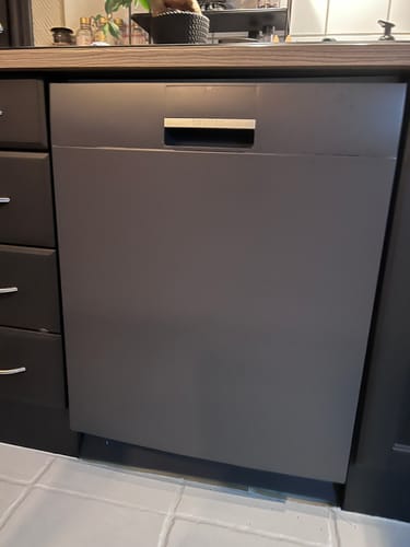 Anmelder viser en oppvaskmaskin som er foliert med matt antrasitt varm grå kontaktplast på et kjøkken.
