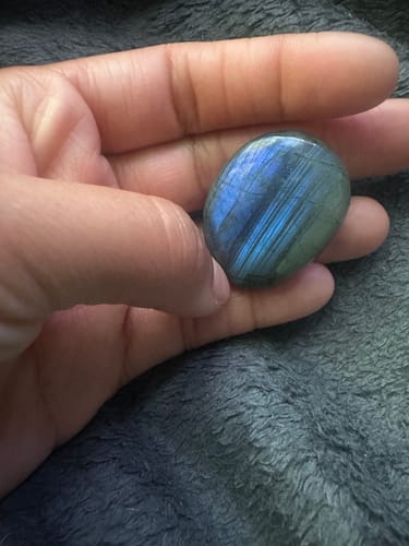 Customer holding a polished labradorite monthly crystal in their palm, showing a vibrant blue flash.
