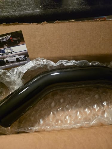 Customer's new glossy black intercooler pipe resting in its original packaging.