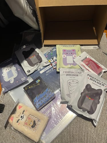 Customer's order showing the Purple Cat Plush Photocard Holder and other items from their haul laid out on the floor.