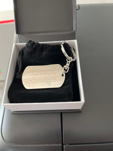 Reviewer's engraved personalized keychain resting in its open white gift box.