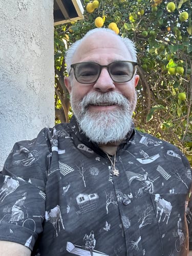 Customer smiles while wearing the patterned "Wicked Winds" short sleeve shirt outdoors.