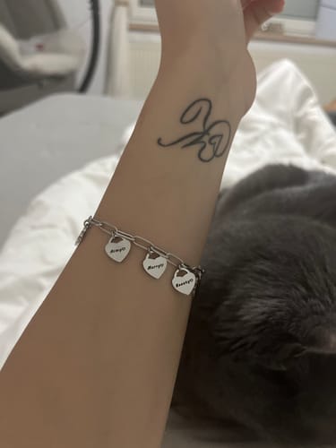 Eine Kundin trägt das silberfarbene Armband mit drei gravierten Herzanhängern am Handgelenk.