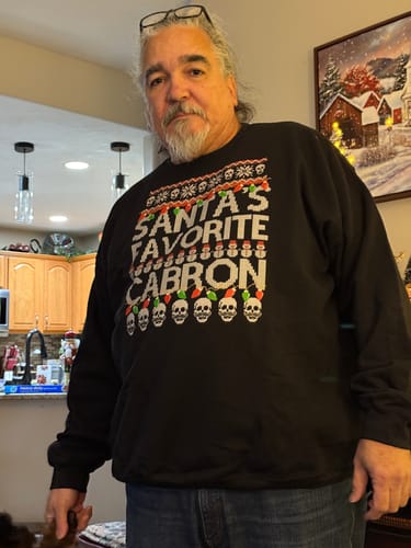 Reviewer wearing the black Santa's Favorite Cabron OG Navidad Sweatshirt indoors.
