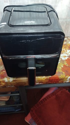 Recenzent prezintă friteuza cu aer cald Novio StonePro neagră pe o masă.