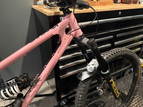 Customer's black Custom Fender with a face graphic, installed on the front fork of a pink mountain bike.