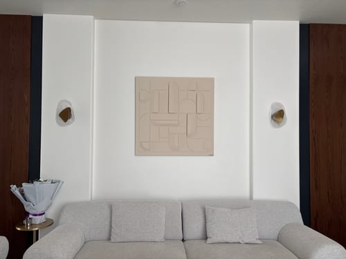 Customer's light beige collage painting hung on a white wall above a sofa in a living room.