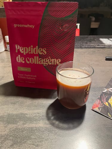 Sachet rose de Peptides de Collagène d'un client à côté d'un verre de boisson préparée.