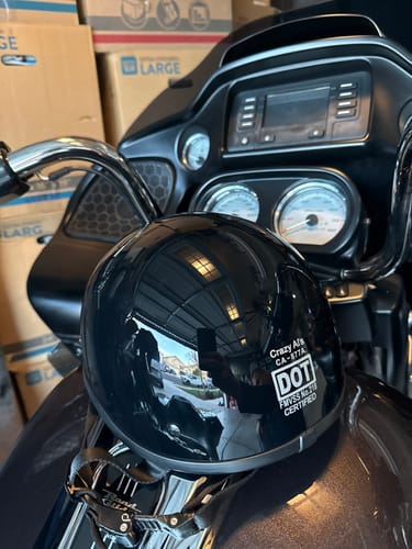Customer's glossy black DOT Beanie helmet resting on the seat of their motorcycle.