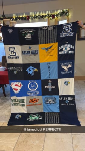 Customer holding up their finished Premium T Shirt Quilt made from various blue and gray wrestling team shirts.
