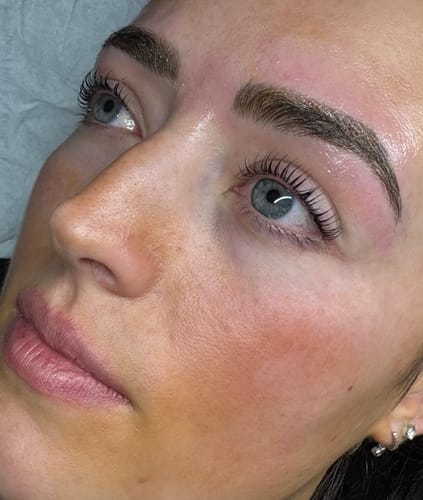 Customer's photo of a client's face, showcasing the final results of a lash lift with dark, curled lashes.