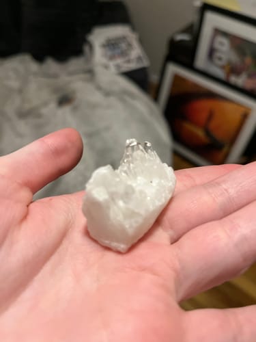 Reviewer holding a small, clear quartz crystal cluster in the palm of their hand.