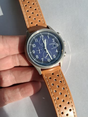 A customer's Citizen-Garrison watch featuring the tan perforated Leather Sport Grip strap, held in hand.