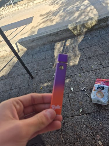 Customer holding the ROLLZ live resin vape pen, which has a purple and orange gradient color.
