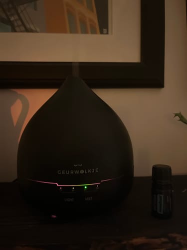 Bewertung eines Kunden: Der mattschwarze Unity 2.0 Diffuser in einem schwach beleuchteten Raum, eingeschaltet mit sichtbarem Nebel.