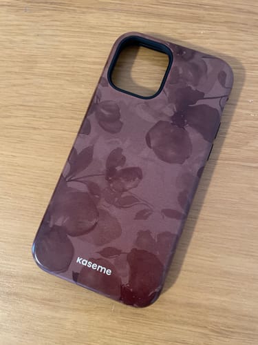Customer's Longchamp Mocha phone case with a tonal floral pattern, lying on a wooden surface.
