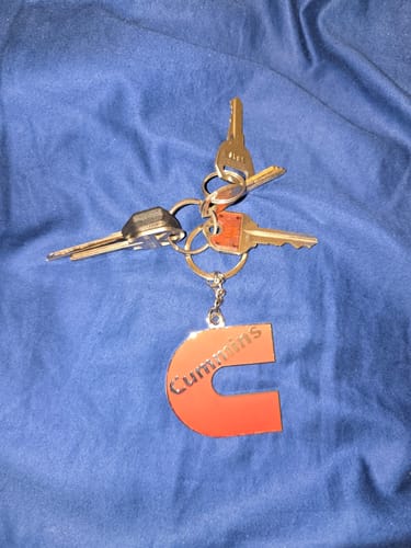Customer's red Cummins keychain attached to a set of keys on a blue background.
