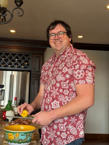 Customer smiling in a kitchen while wearing the red, festive Disney "Orna-Mickeys" shirt.