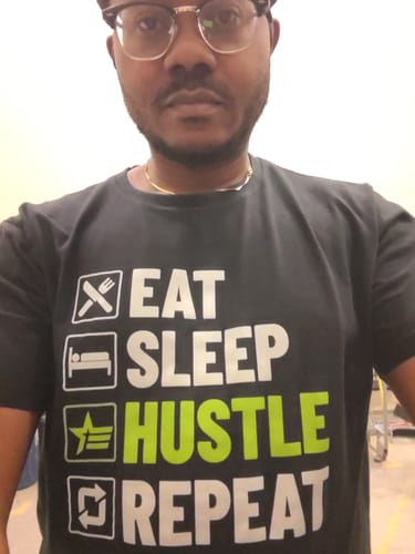 Customer wearing the black Cycle Tee with its 'Eat Sleep Hustle Repeat' graphic.