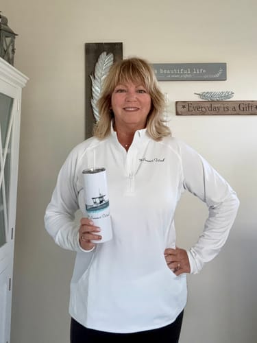 Customer holding a white custom tumbler and wearing a matching white quarter-zip pullover.