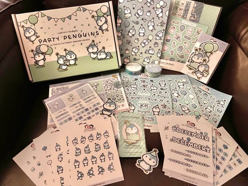 Reviewer's 'Party Penguins' Ultimate Subscription showing the illustrated box, sticker sheets, washi tape, and enamel pin.