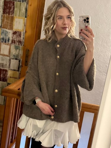Kundin trägt den Oversized-Cardigan "CozyGlam" aus Grobstrick über dem weißen Volant-Rock "Summer".