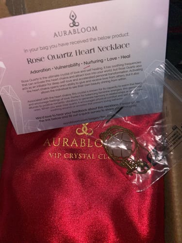 Customer's Rose Quartz heart necklace from the AuraBloom box, shown with its red pouch and info card.