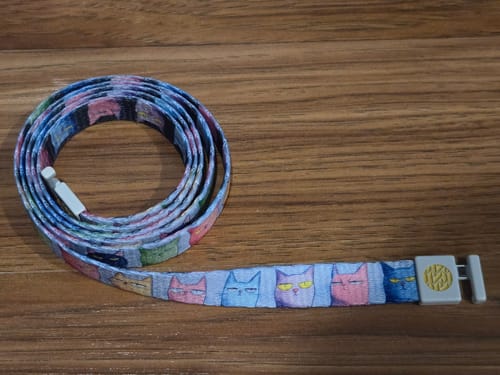 Customer's 'I do What I Want String' with a colorful cat face pattern, coiled up on a wooden surface.