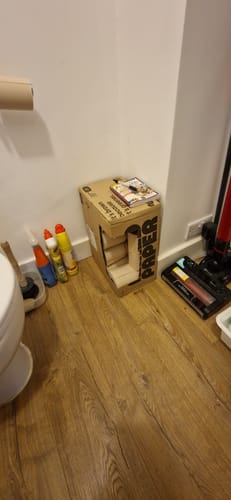 Reviewer's recyclable box of Unbleached Bamboo Toilet Paper stored in the corner of a bathroom.