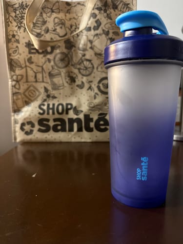 Le client montre son shaker Shop Santé, un cadeau avec un dégradé de bleu.